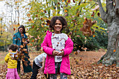 Portrait happy girl playing with family in autumn leaves