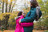 Happy mother and daughter hugging in autumn woods