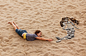 Girl mimicking rock mermaid on beach