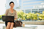 Smiling businesswoman with laptop outdoors