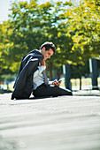 Smiling businessman using cell phone in park