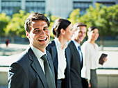 Happy businessman walking with colleagues outdoors