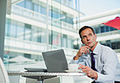 Pensive businessman drinking coffee at laptop