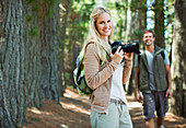 Smiling woman with digital camera in woods
