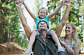 Father carrying daughter on shoulders in woods