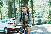 Smiling man riding mountain bike in woods