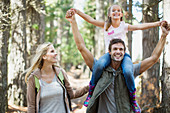 Father carrying daughter on shoulders in woods