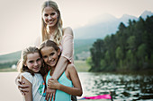 Mother and daughters smiling at lakeside