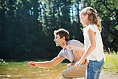 Father and daughter skipping stones at lakeside