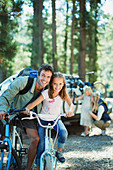 Smiling father and daughter on bicycles in woods