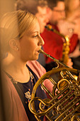 Woman playing french horn in orchestra
