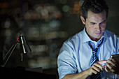 Businessman using cell phone in office at night