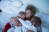 Mother with sons sleeping in bed