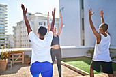 Friends practicing yoga on sunny urban rooftop