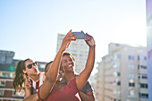 Young friends taking selfie with on sunny urban rooftop
