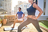 Young couple practicing yoga on sunny urban rooftop