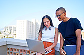 Young business people with laptop working on urban rooftop