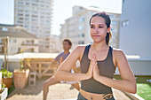 Confident young woman practicing yoga on sunny rooftop