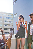 Cool young woman gesturing peace sign on sunny urban rooftop