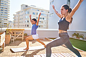 Young couple practicing yoga on sunny urban rooftop balcony