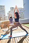 Young couple practicing yoga on sunny urban rooftop balcony