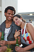 Happy young friends drinking beer on patio