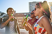 Happy young friends dancing and drinking beer on rooftop