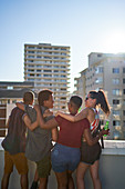 Happy young friends hanging out on sunny rooftop balcony