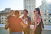 Happy young friends dancing on urban rooftop balcony