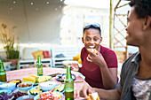 Portrait happy young woman eating taco at patio table