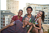 Portrait happy young friends hanging out on sunny rooftop