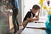 Focused boy homeschooling at kitchen table