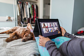 Woman video chatting with friends on bed with dog