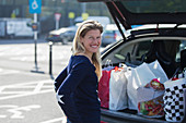 Portrait happy woman with grocery bags at bag of car