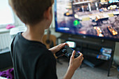 Boy playing video game at TV in living room