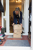 Woman retrieving produce boxes from front stoop
