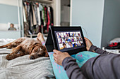 Woman video chatting with friends on bed with dog