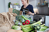 Woman unloading fresh produce from box in kitchen