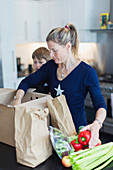 Mother and son unloading fresh produce in kitchen