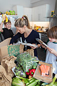 Woman and sons unloading fresh produce from box in kitchen