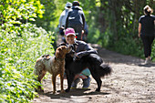 Happy woman hiking on sunny trail with dogs