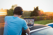 Man with headphones and laptop video chatting with friends