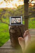 POV barefoot man video chatting with friends on tablet