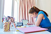 Girl homeschooling at desk in bedroom