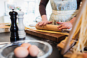 Woman rolling dough with rolling pin in kitchen
