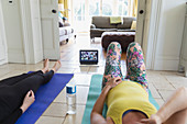 Women practicing yoga online with laptop at home