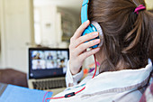 Teenage girl with headphones video chatting at laptop