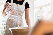 Woman pouring water into bowl for baking