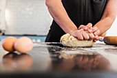 Close up woman kneading dough on kitchen counter