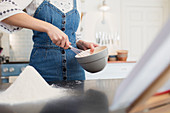Teenage girl with whisk and bowl baking in kitchen